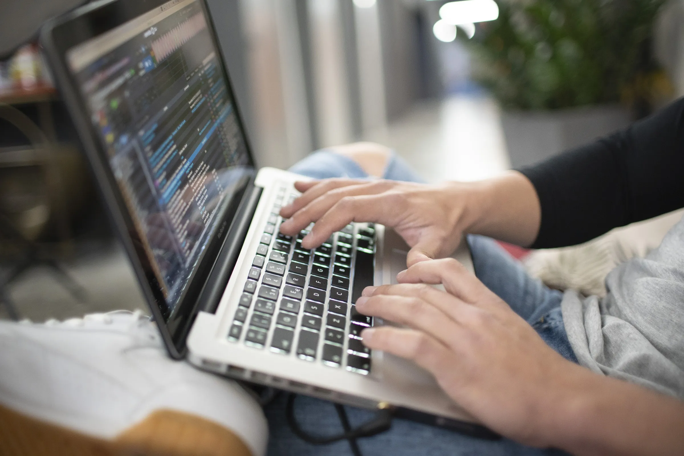 Manos sobre el teclado de un portátil con el software de DJ en pantalla